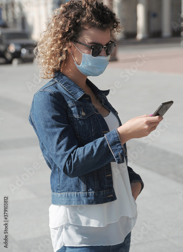 Curly hair woman works on mobile phone outdoors 