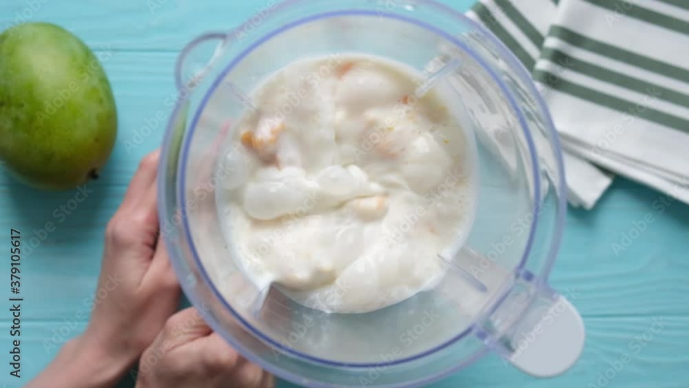 Mango milkshake or mango lassi blending. Slow motion of mixing milk with mango and banana in a blender Mango milkshake or mango lassi blending. Slow motion of mixing milk with mango and banana in a blender
