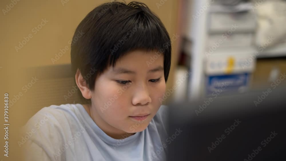 Asian Boy using a computer desktop playing Asian Boy using a computer desktop playing