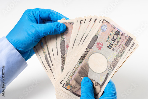 Man's hands in blue nitrile glove holding bank notes photo