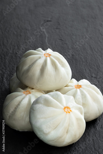 Steamed bao buns with delicious filling on black stone background