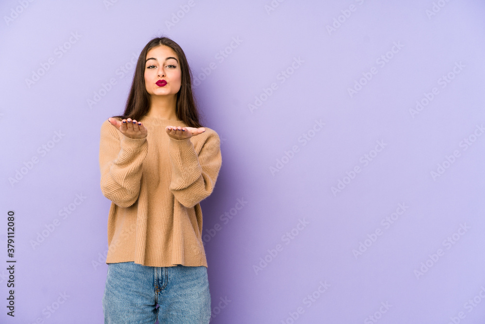 Young caucasian woman isolated on purple background folding lips and holding palms to send air kiss. Young caucasian woman isolated on purple background folding lips and holding palms to send air kiss.