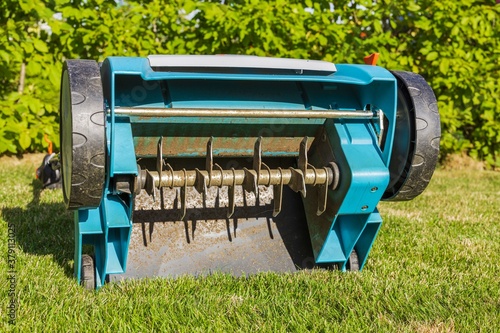 Close uo view of electric lawn aerator on green grass isolated. Garden machines concept. 