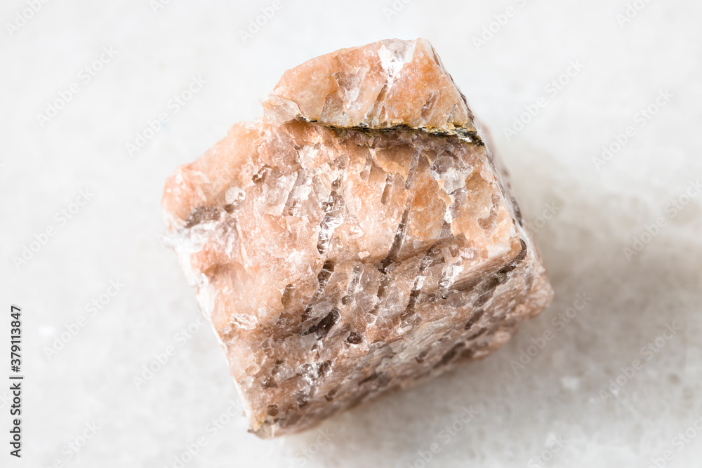 closeup of sample of natural mineral from geological collection - unpolished Granite Pegmatite rock on white marble background closeup of sample of natural mineral from geological collection - unpolished Granite Pegmatite rock on white marble background