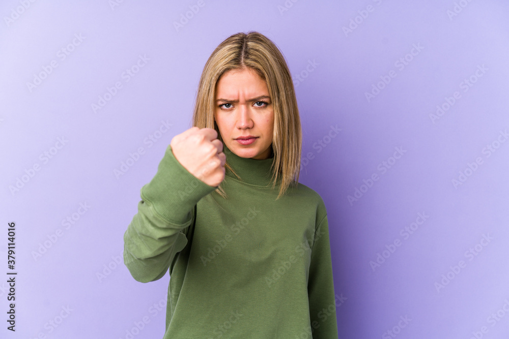 Young blonde caucasian woman isolated showing fist to camera, aggressive facial expression. Young blonde caucasian woman isolated showing fist to camera, aggressive facial expression.