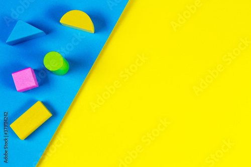 Fototapeta Naklejka Na Ścianę i Meble -  Wooden colorful blocks on geometric yellow and blue background. Top view, flat lay