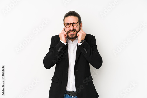 Young caucasian business man isolated on a white background covering ears with hands.