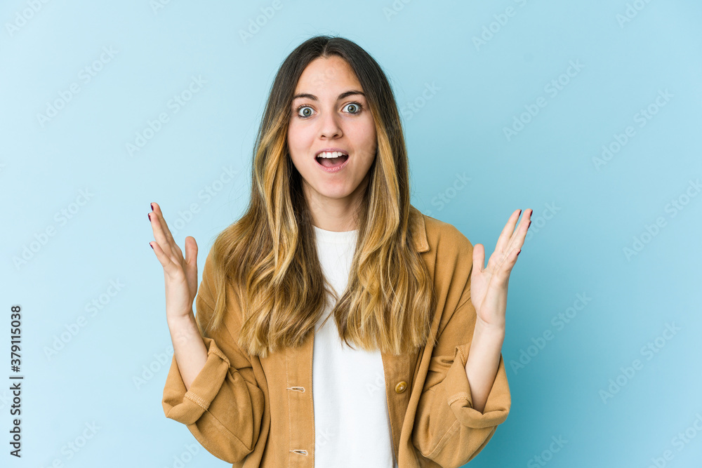 Young caucasian woman isolated on blue background celebrating a victory or success, he is surprised and shocked. Young caucasian woman isolated on blue background celebrating a victory or success, he is surprised and shocked.
