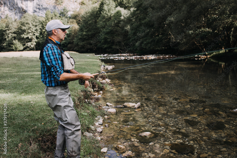 Senior man is fishing alone on fast mountain river. Active people and sport fly fishing concept. Senior man is fishing alone on fast mountain river. Active people and sport fly fishing concept.