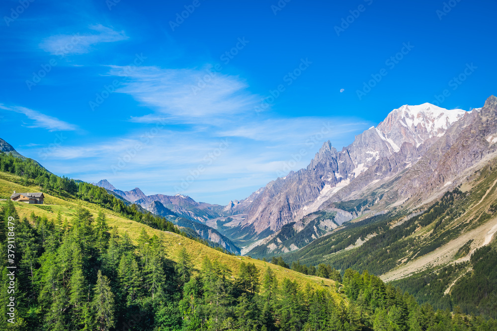 Early morning azure sky and the moon with refuge Bonatti overseeing the Great Jorasses and the valley, Tour du Mont Blanc, Italian Alpses