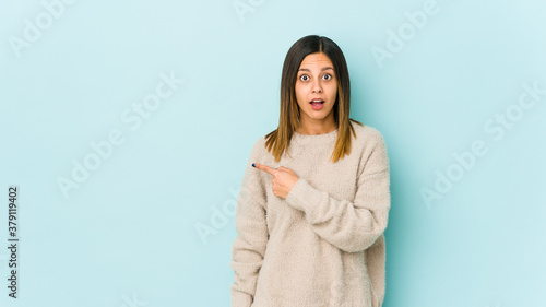 Young woman isolated on blue background pointing to the side