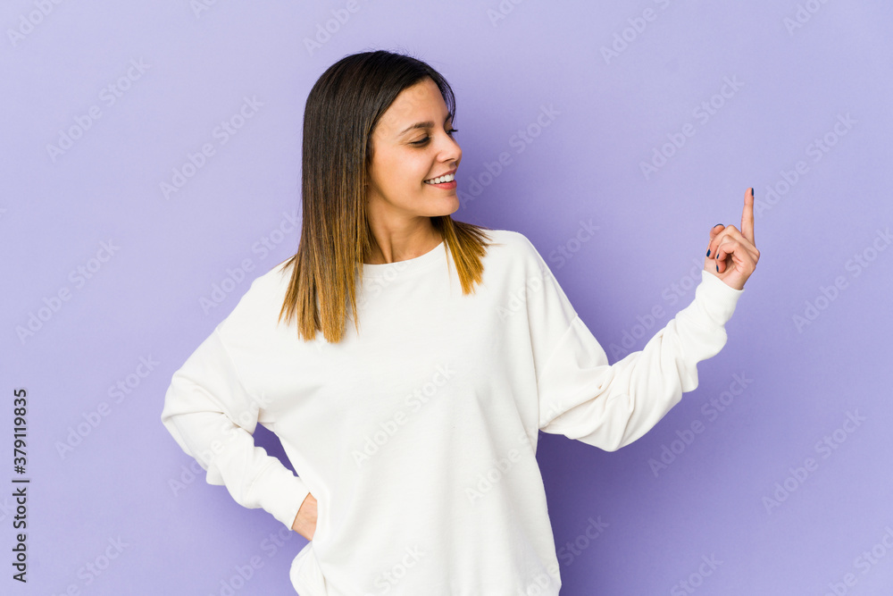 Young woman isolated on purple background pointing with finger at you as if inviting come closer. Young woman isolated on purple background pointing with finger at you as if inviting come closer.