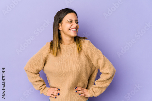 Young woman isolated on purple background laughs and closes eyes, feels relaxed and happy.