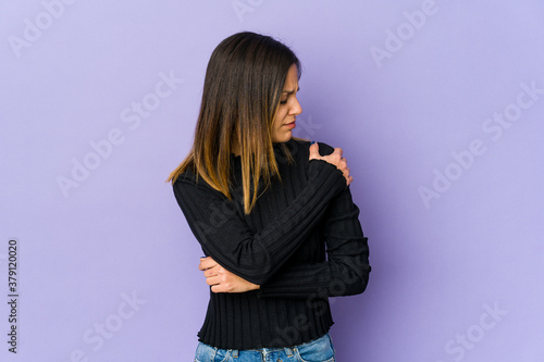 Young woman isolated on purple background having a shoulder pain.