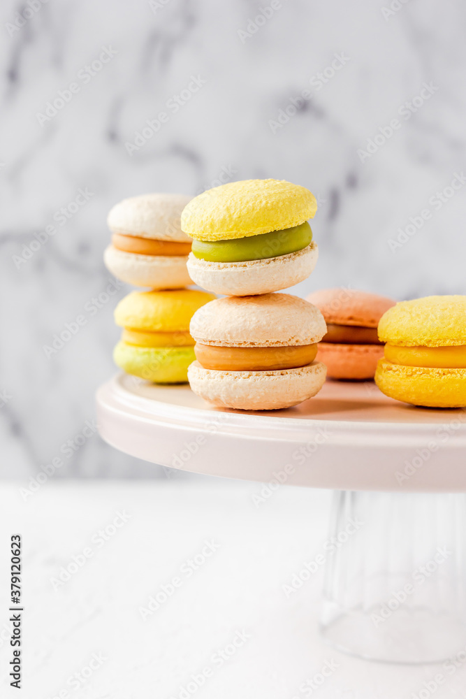 Colorful french macarons on a pink plate on marble background