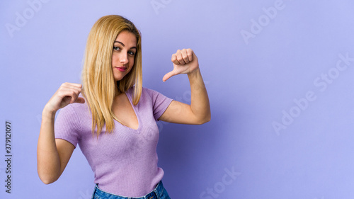 Young blonde woman isolated on purple background feels proud and self confident, example to follow.