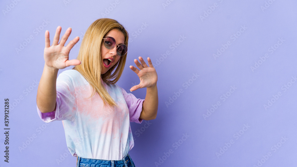 Young hipie woman with glasses isolated on purple background being shocked due to an imminent danger Young hipie woman with glasses isolated on purple background being shocked due to an imminent danger