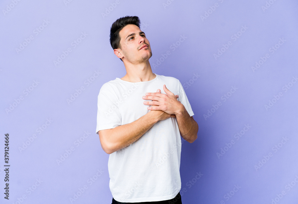 Young caucasian man isolated on purple background has friendly expression, pressing palm to chest. Love concept. Young caucasian man isolated on purple background has friendly expression, pressing palm to chest. Love concept.
