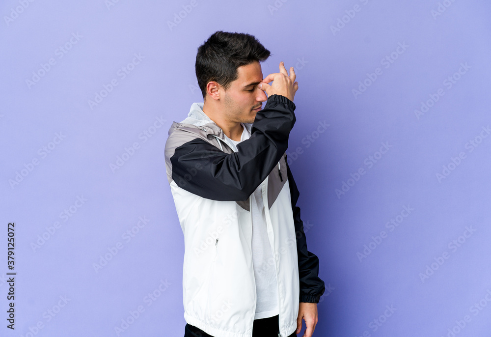 Young caucasian man isolated on purple background having a head ache, touching front of the face.