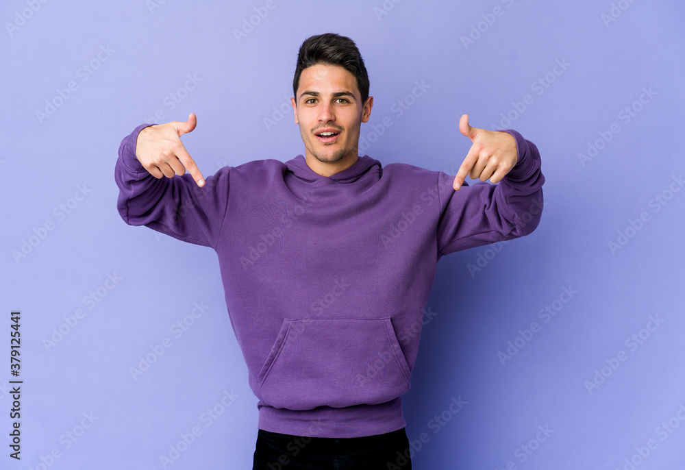Fototapeta premium Young caucasian man isolated on purple background points down with fingers, positive feeling.