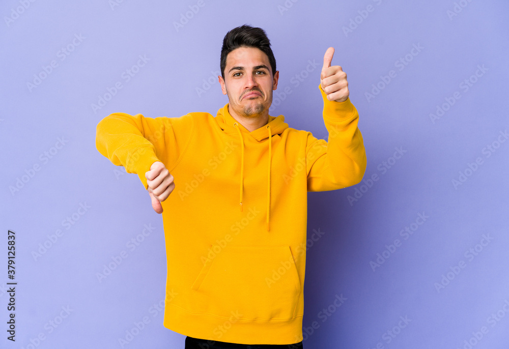 Young caucasian man isolated on purple background showing thumbs up and thumbs down, difficult choose concept Young caucasian man isolated on purple background showing thumbs up and thumbs down, difficult choose concept