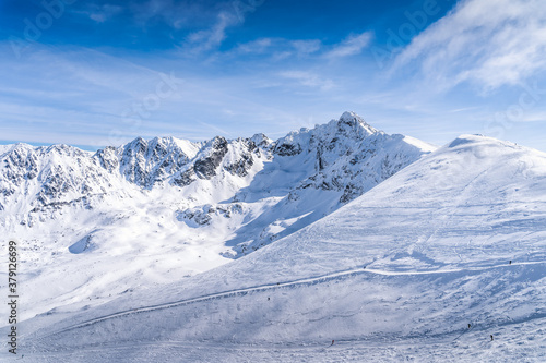 People skiing and snowboarding from Kasprowy Wierch, winter holidays. Amazing mountain range with snow capped mountain peaks in Tatra Mountains Poland