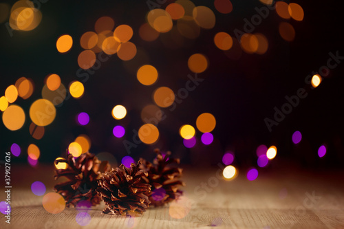 Christmas lights in out of focus, pine cones on a wooden Board, dark background