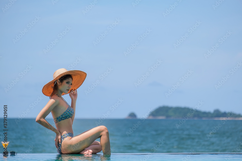 Happy woman asia enjoying beach relaxing joyful in summer by tropical blue water. Beautiful bikini orange tan skin model happy on travel wearing beach sun hat on rayong beach, Rayong, Thailand Happy woman asia enjoying beach relaxing joyful in summer by tropical blue water. Beautiful bikini orange tan skin model happy on travel wearing beach sun hat on rayong beach, Rayong, Thailand