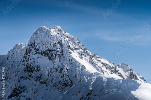 View from Kasprowy Wierch on adventurers who climbed on Swinica mountain peak at winter. Tatra Mountains range with snow capped mountain peaks  Poland