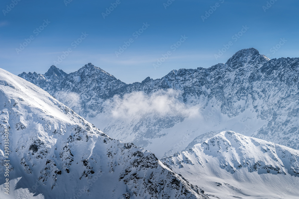 View from Kasprowy Wierch at rocky mountain peak at winter. Amazing mountain range with snow capped mountain peaks in Tatra Mountains, Poland