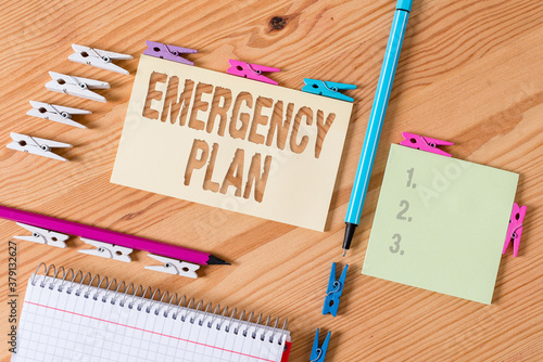 Writing note showing Emergency Plan. Business concept for instructions that outlines what workers should do in danger Colored clothespin papers empty reminder wooden floor background office