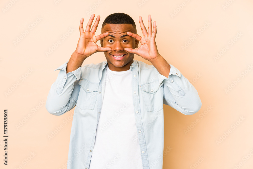 Young latin man isolated on beige background keeping eyes opened to find a success opportunity.