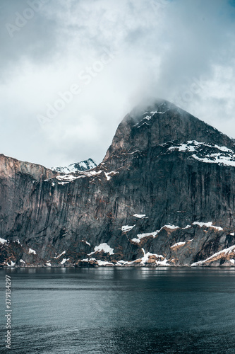 Segla - characteristic mountain on the Senja island  northern Norway. Part of the fjord. Arctic sea  rocks  grey clouds and snow. 