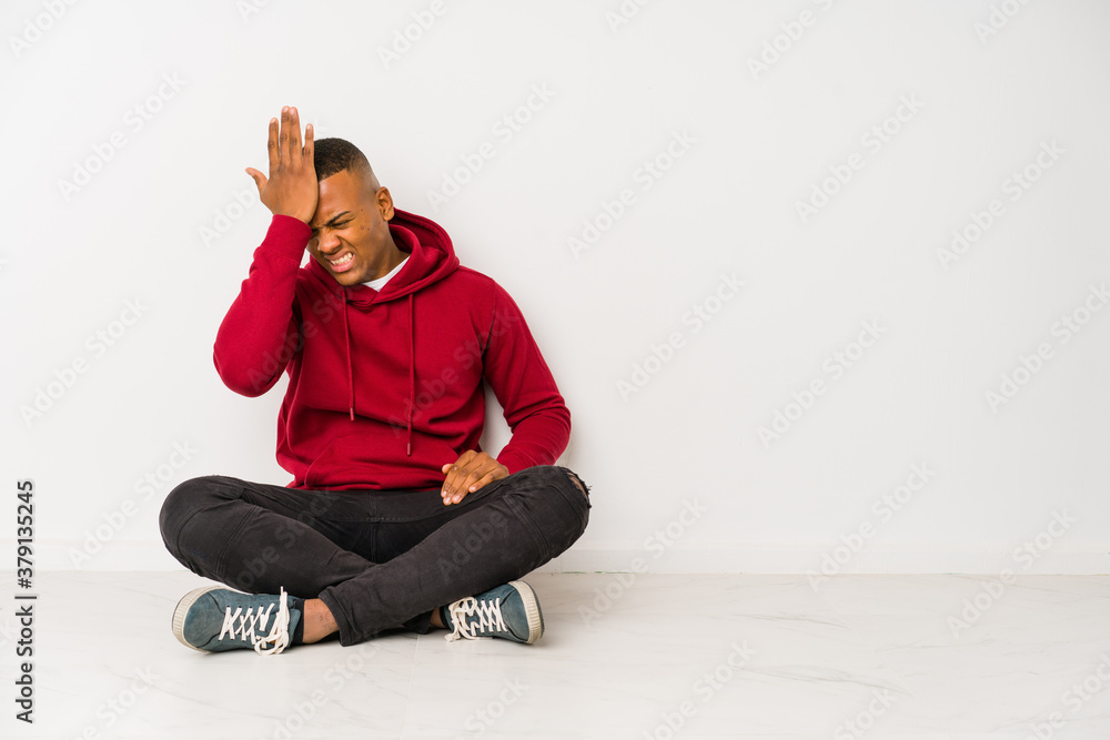 Young latin man sitting on the floor isolated forgetting something, slapping forehead with palm and closing eyes. Young latin man sitting on the floor isolated forgetting something, slapping forehead with palm and closing eyes.
