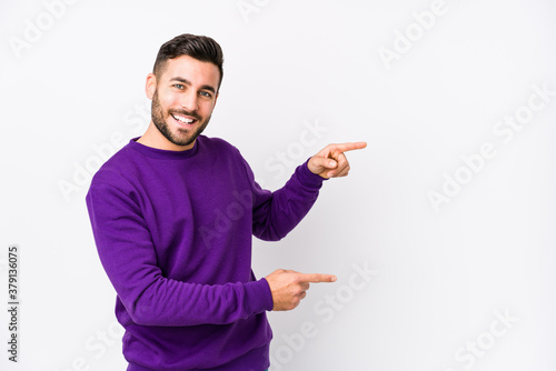Young caucasian man against a white background isolated excited pointing with forefingers away. photo