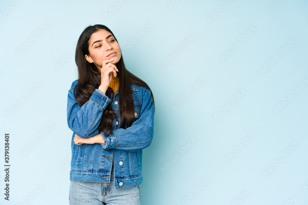 Young indian woman isolated on blue background looking sideways with doubtful and skeptical expression. Young indian woman isolated on blue background looking sideways with doubtful and skeptical expression.