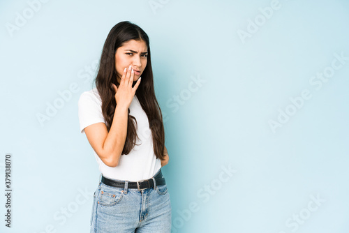 Young indian woman on blue background having a strong teeth pain, molar ache.