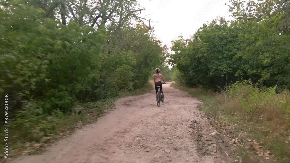 Aerial shot of young sport woman rides bicycle on countryside dusty road at summer evening. Healthy cycling lifestyle Aerial shot of young sport woman rides bicycle on countryside dusty road at summer evening. Healthy cycling lifestyle