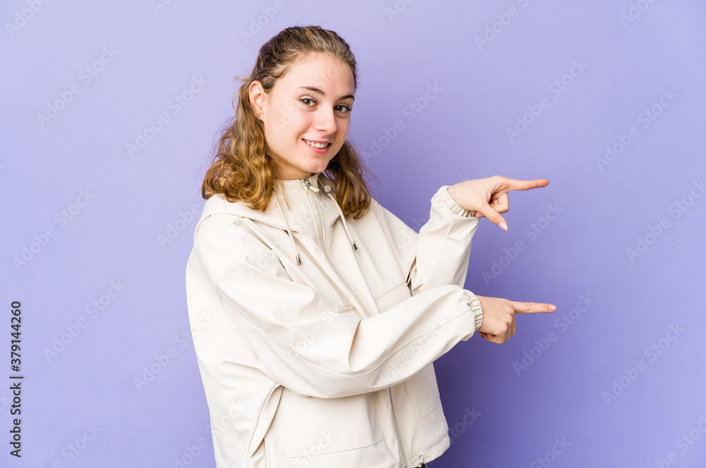 Young caucasian woman on purple background excited pointing with forefingers away. Young caucasian woman on purple background excited pointing with forefingers away.