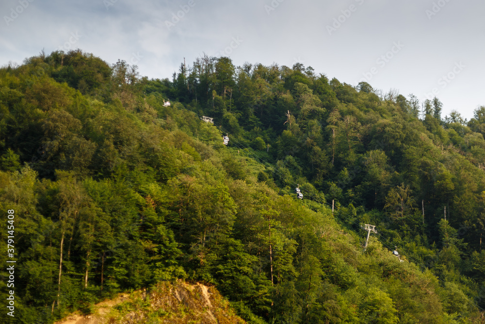 Misty mountain landscape with fir forest. Beautiful landscape with mountain view, cable car. Postcard view. Travel concept. Sunset, Golden hour Misty mountain landscape with fir forest. Beautiful landscape with mountain view, cable car. Postcard view. Travel concept. Sunset, Golden hour