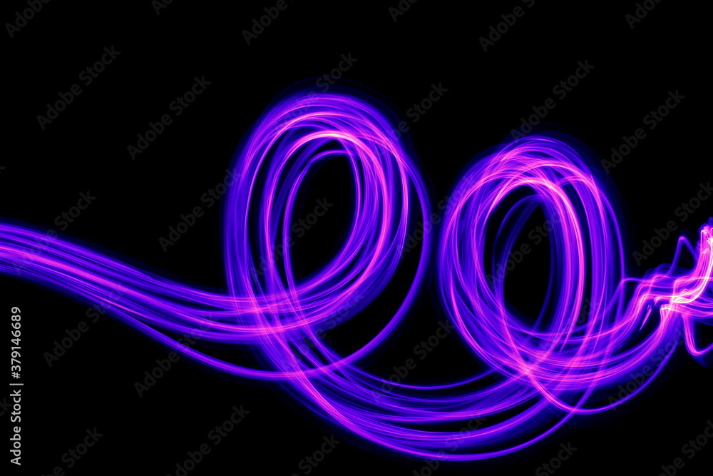 Long exposure photograph of purple neon colour in an abstract swirl, parallel lines pattern against a black background. Light painting photography.