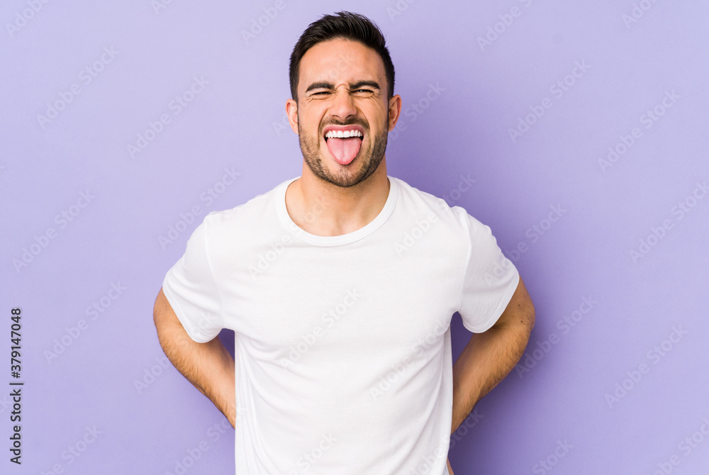 Young caucasian man isolated on purple background funny and friendly sticking out tongue. Young caucasian man isolated on purple background funny and friendly sticking out tongue.
