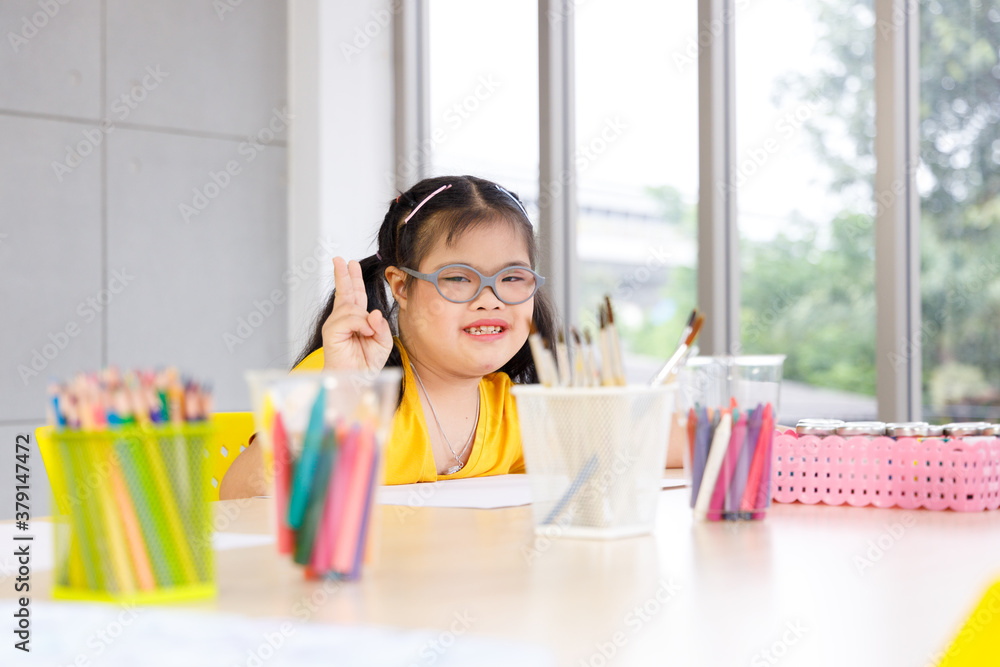 Happy Asian girl with Down's syndrome sit at the desk in classroom. Happy Asian girl with Down's syndrome sit at the desk in classroom.