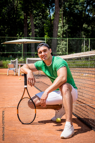 Portrait of young athletic man on tennis court. © romaset