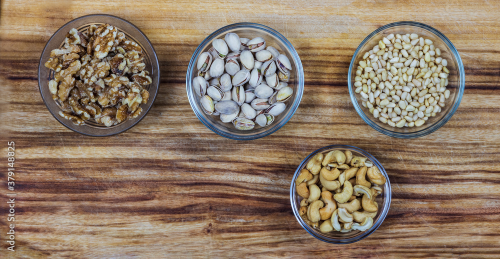 glass bowls with different nuts on wooden board glass bowls with different nuts on wooden board