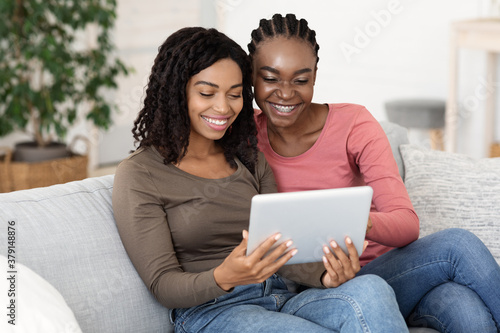 Smiling black women using digital tablet at home