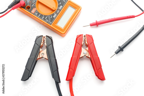 Red and black cooper jumper cable with multimeter voltmeter isolated on white background. Car battary service concept. Top view. photo