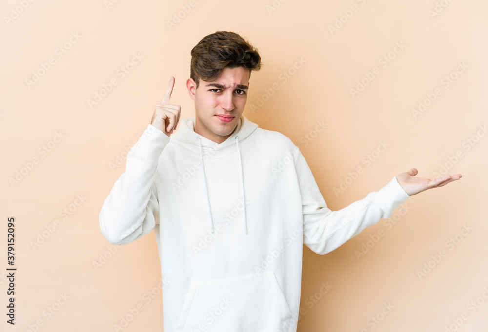 Young caucasian man isolated on beige background holding and showing a product on hand. Young caucasian man isolated on beige background holding and showing a product on hand.