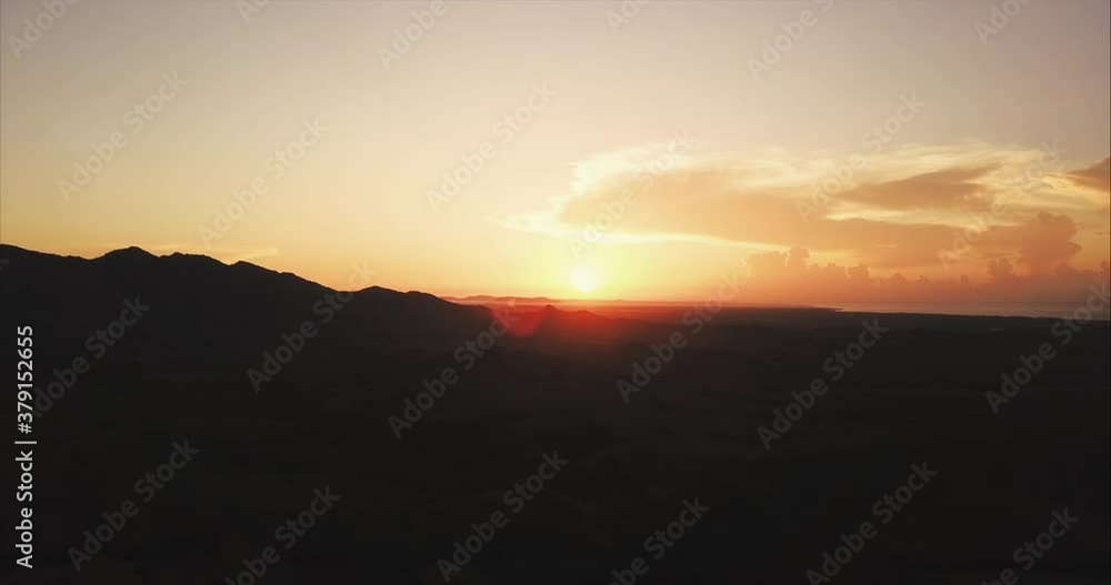 Aerial view of beautiful sunrise in the mountains. The sun rises from the horizon and illuminates the valley and silhouettes of peaks Aerial view of beautiful sunrise in the mountains. The sun rises from the horizon and illuminates the valley and silhouettes of peaks
