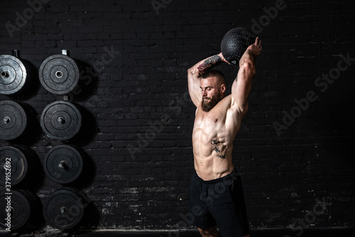 Canvas Print Young sweaty strong muscular fit man with big muscles doing ball throwing on the